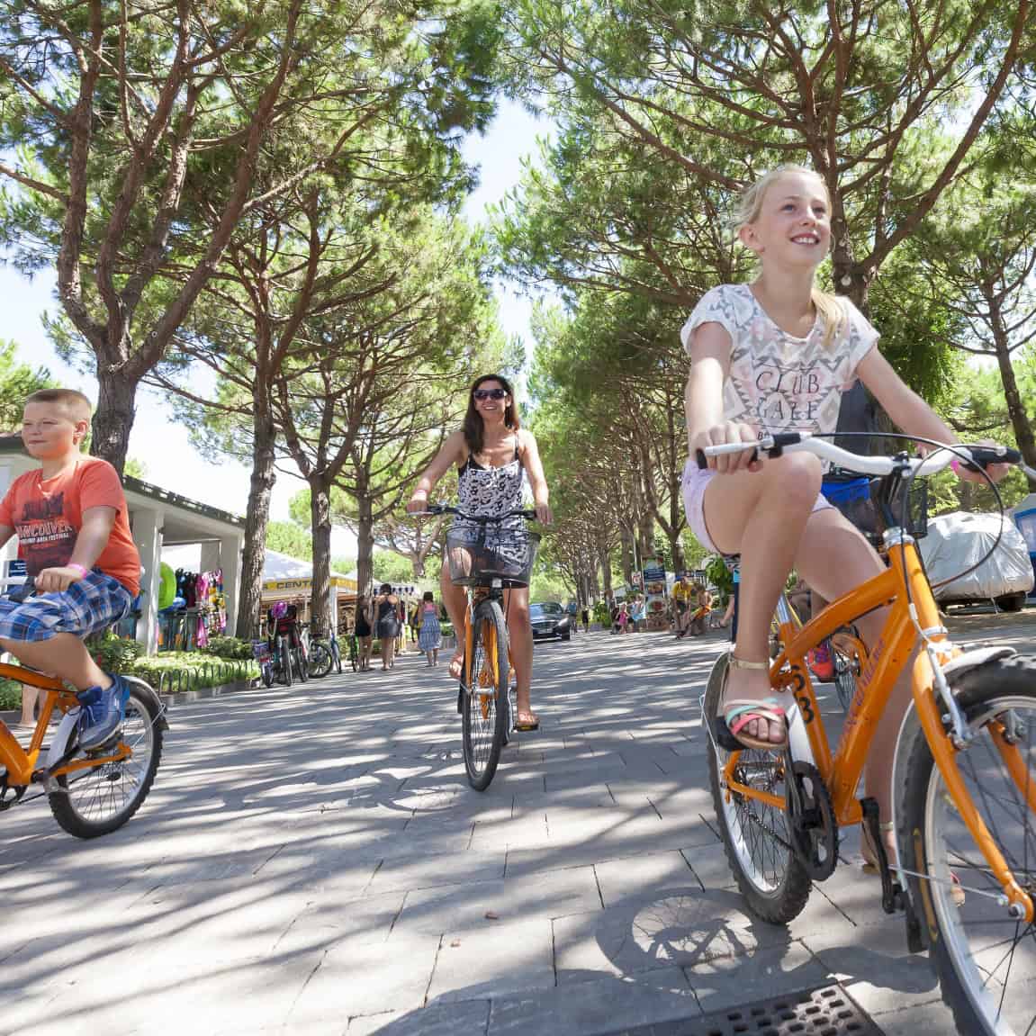 Mamma e bambini in bici sul viale del villaggio
