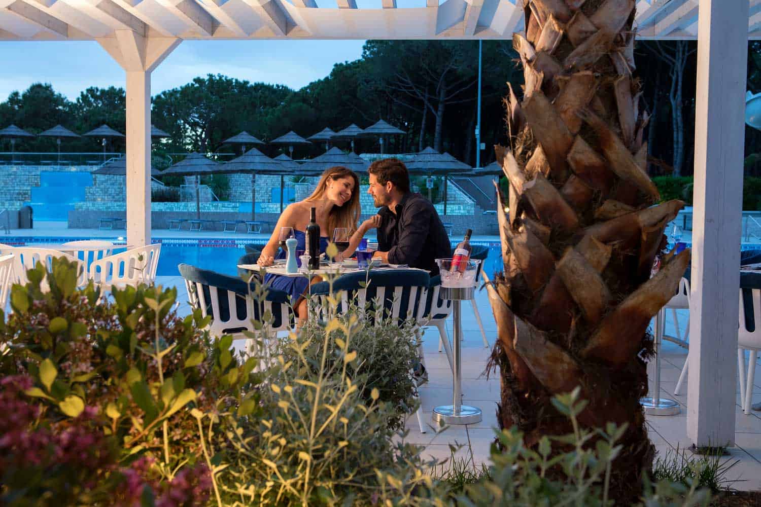 Una coppia cena a bordo piscina al ristorante del Villaggio