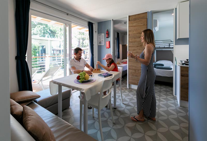 Famiglia nel soggiorno di una mobile home con papà e figlia che giocano a forza