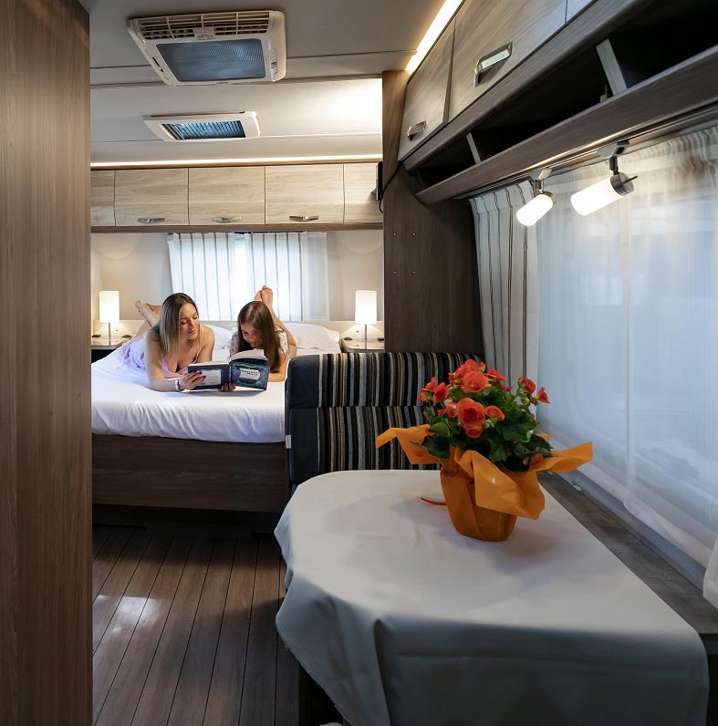 Mamma e figlia leggono un libro nel letto di una Caravan Fronte Mare