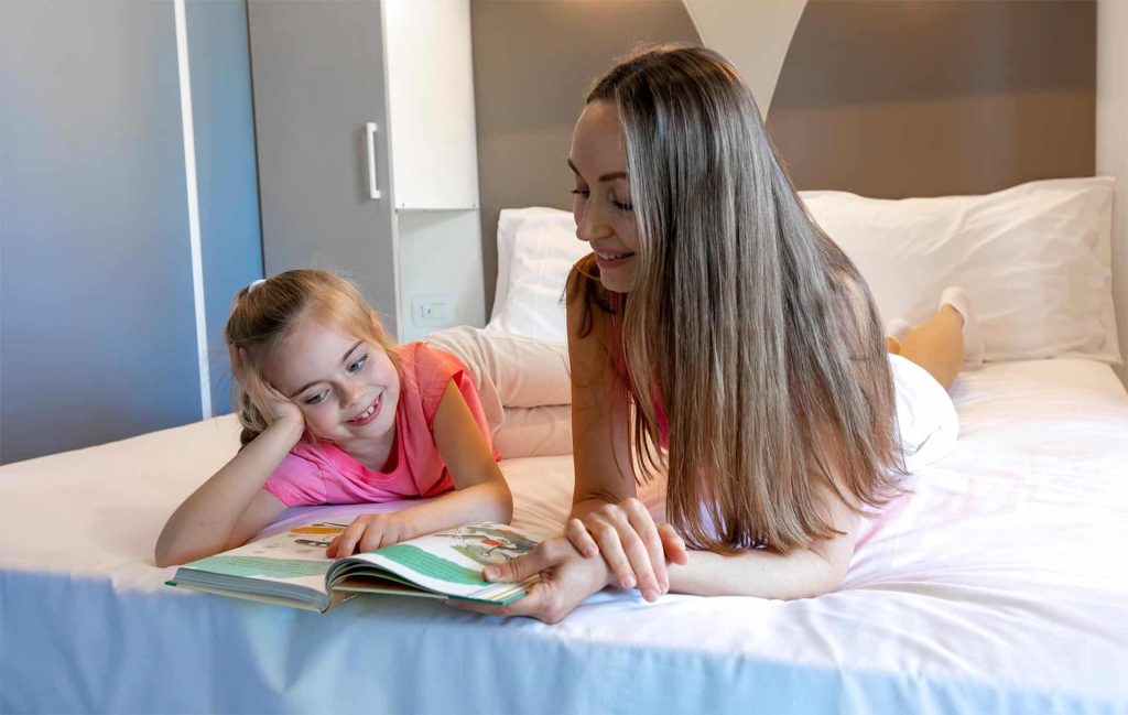 Mamma e figlia leggono un libro sul letto di una Mobile Home